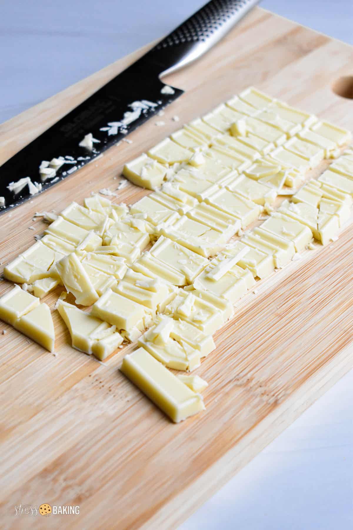 Chopped white chocolate bar on a cutting board with a chef's knife