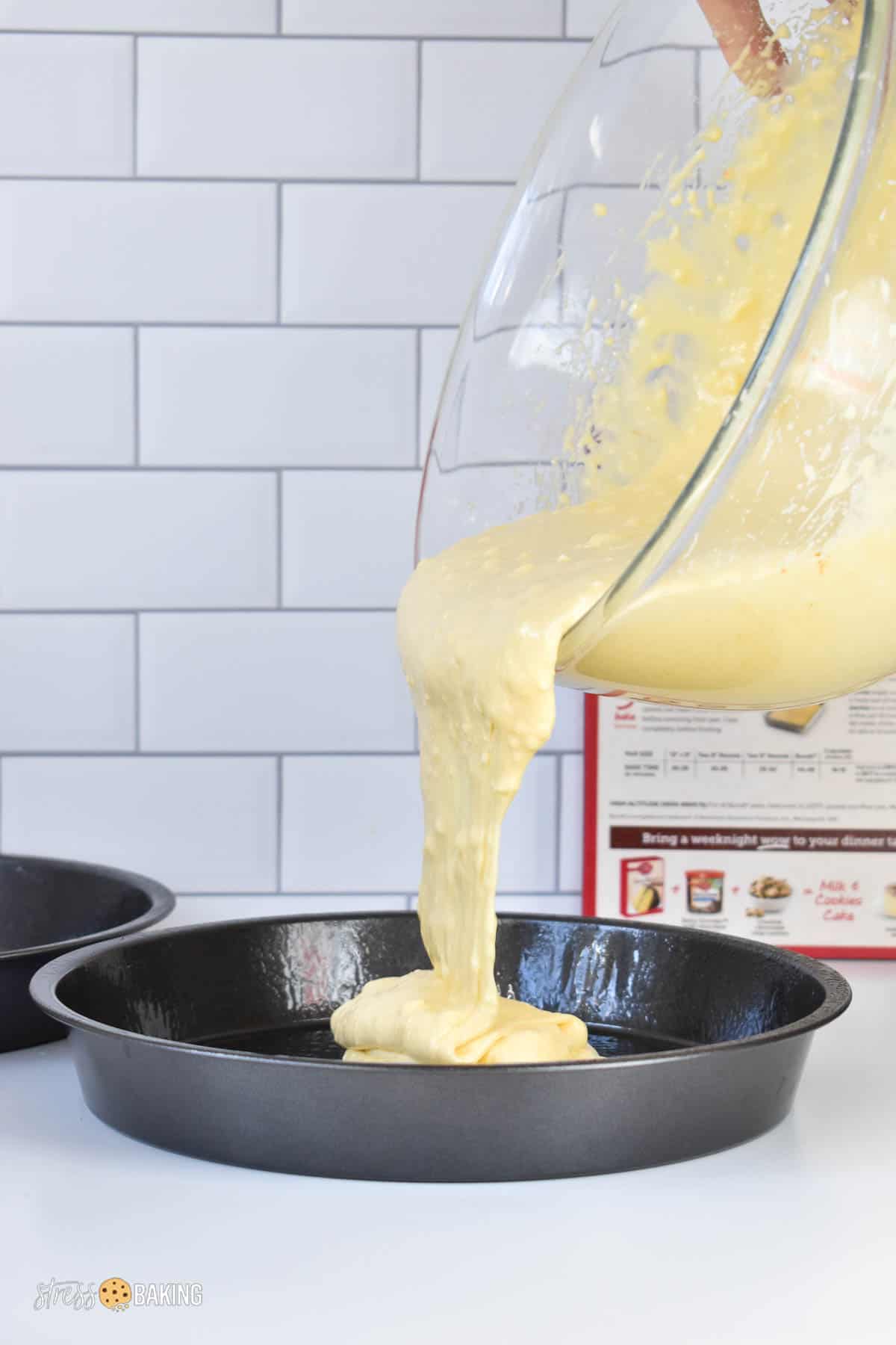 Vanilla cake batter being poured into a greased cake pan