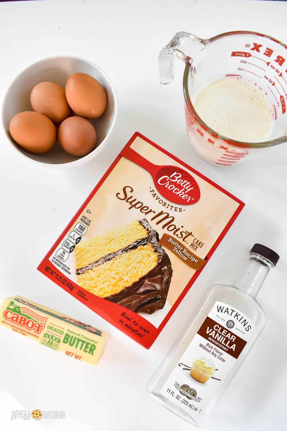 Ingredients for vanilla cake on a white counter with a boxed cake mix
