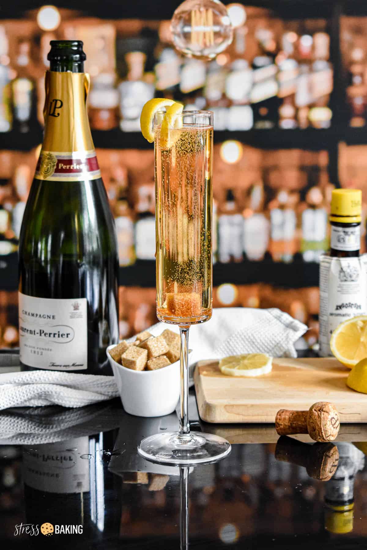 A champagne cocktail on a black bar with a lemon twist garnish