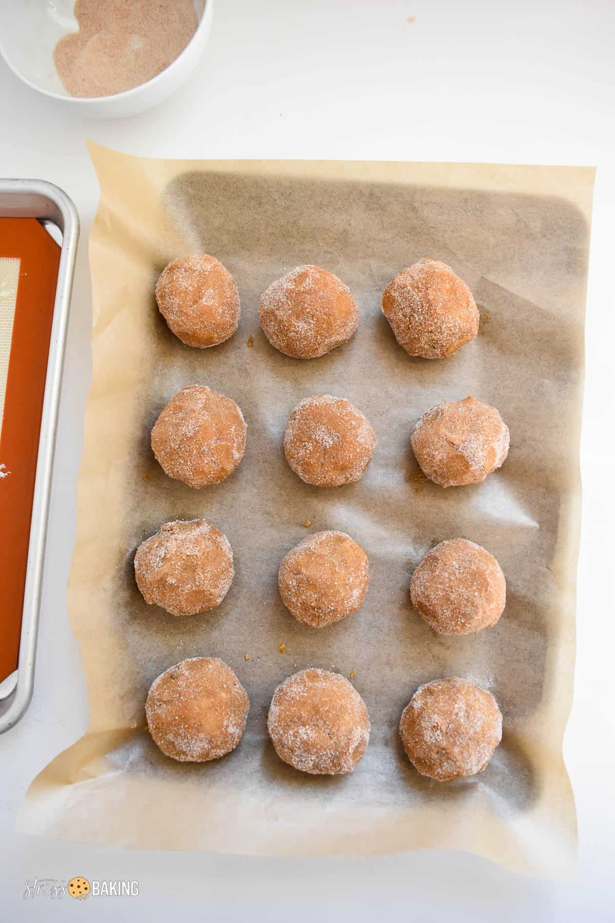 Balls of gingerbread dough coated in sugar on parchment paper