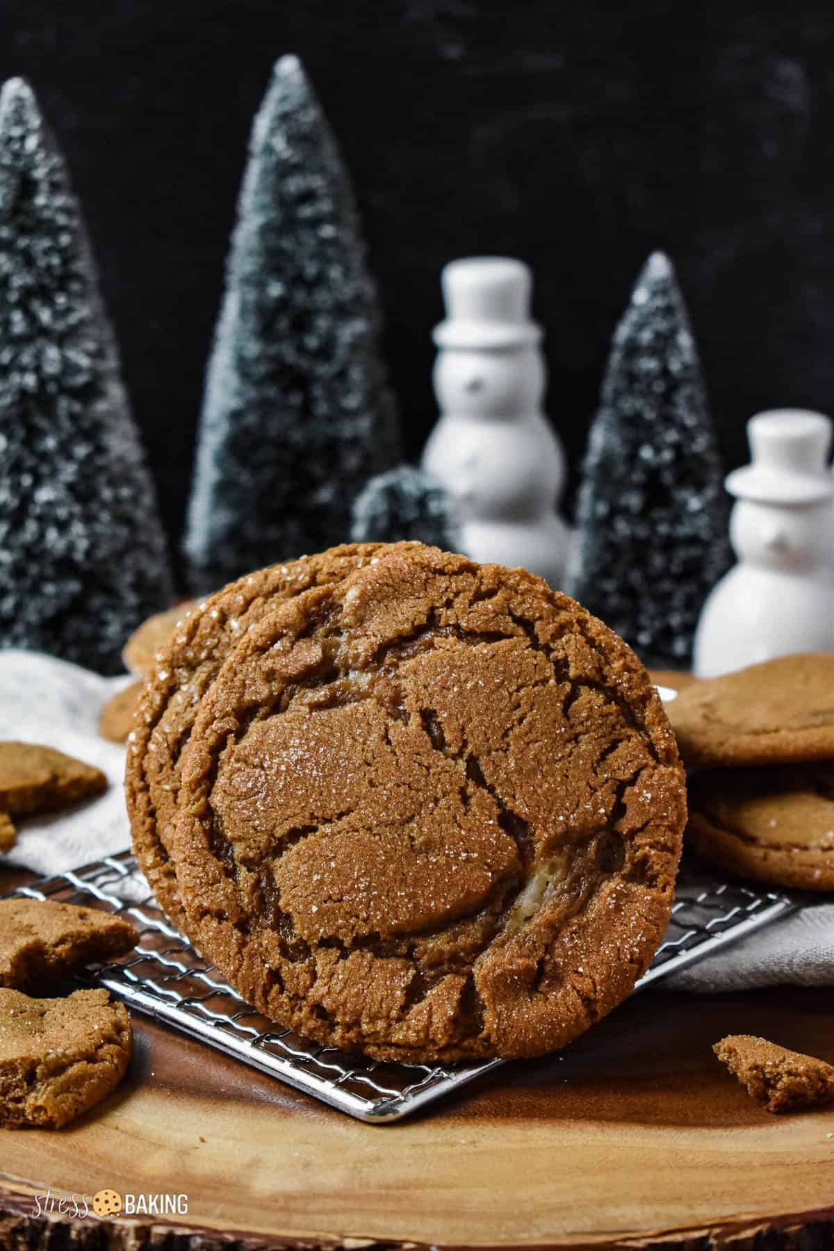 Crinkly gingerbread cookies on a wood platter with a festive holiday background of trees and snowmen