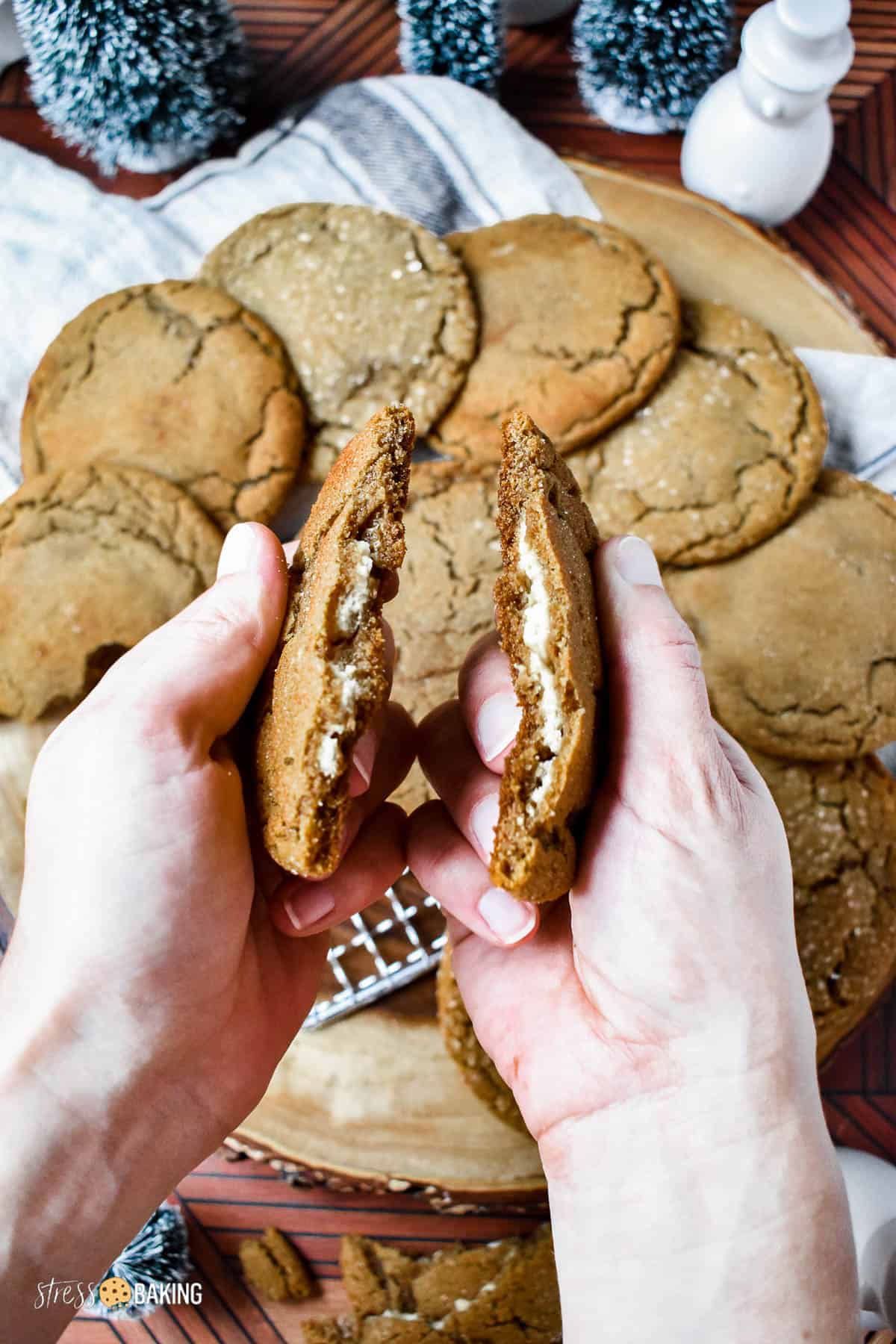 A soft and chewy gingerbread cookie broken in half to show the cheesecake filling inside