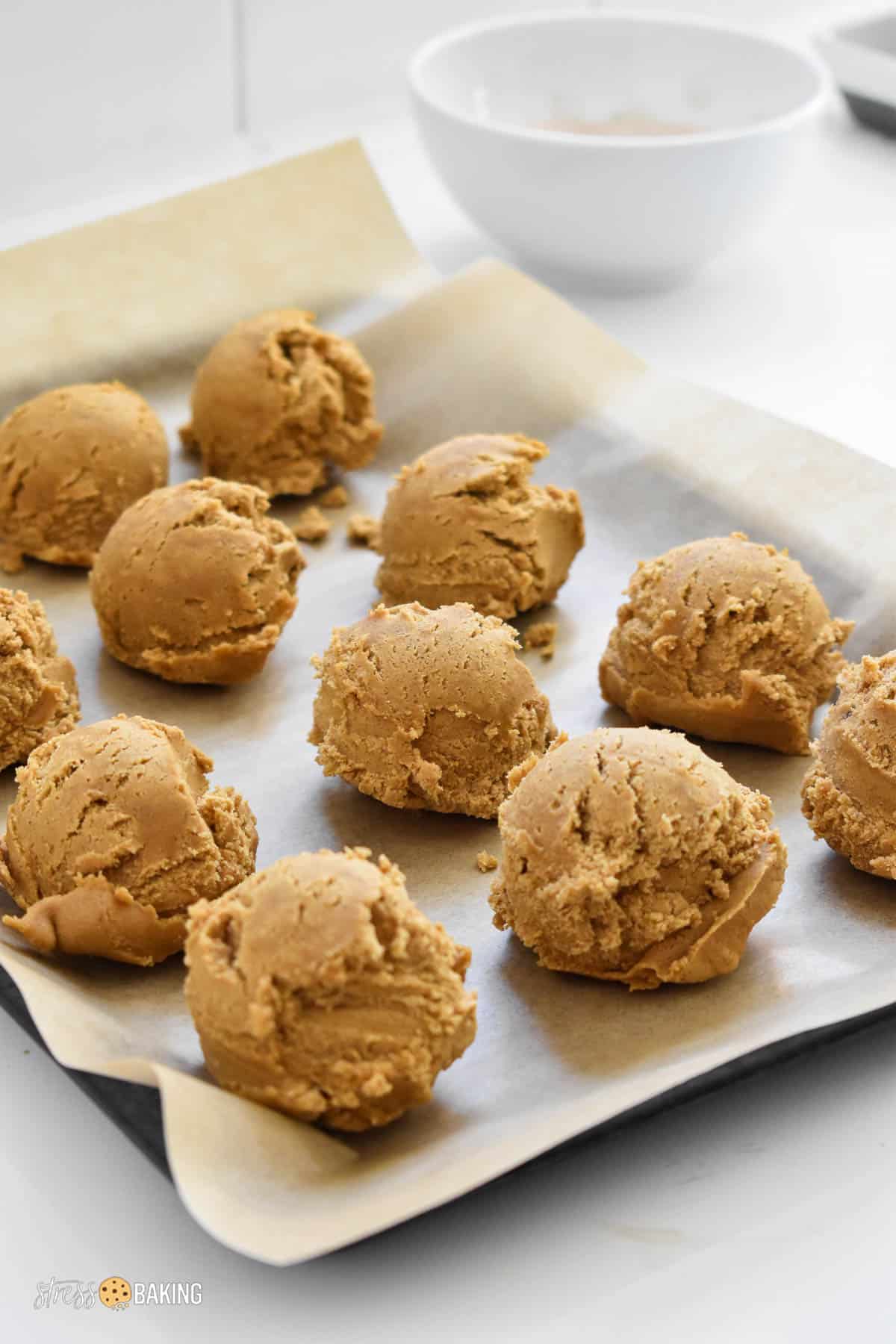 Gingerbread cheesecake cookie dough balls on a baking sheet with parchment paper