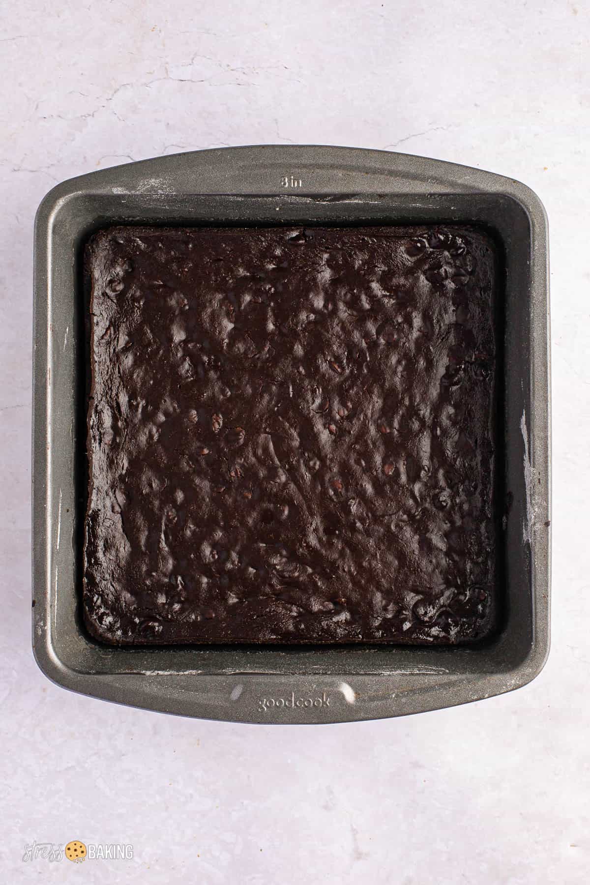 Square baking pan of dark chocolate brownies with a crackly top