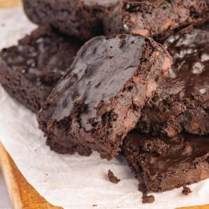 Super fudgy brownie leaning on a pile of brownies