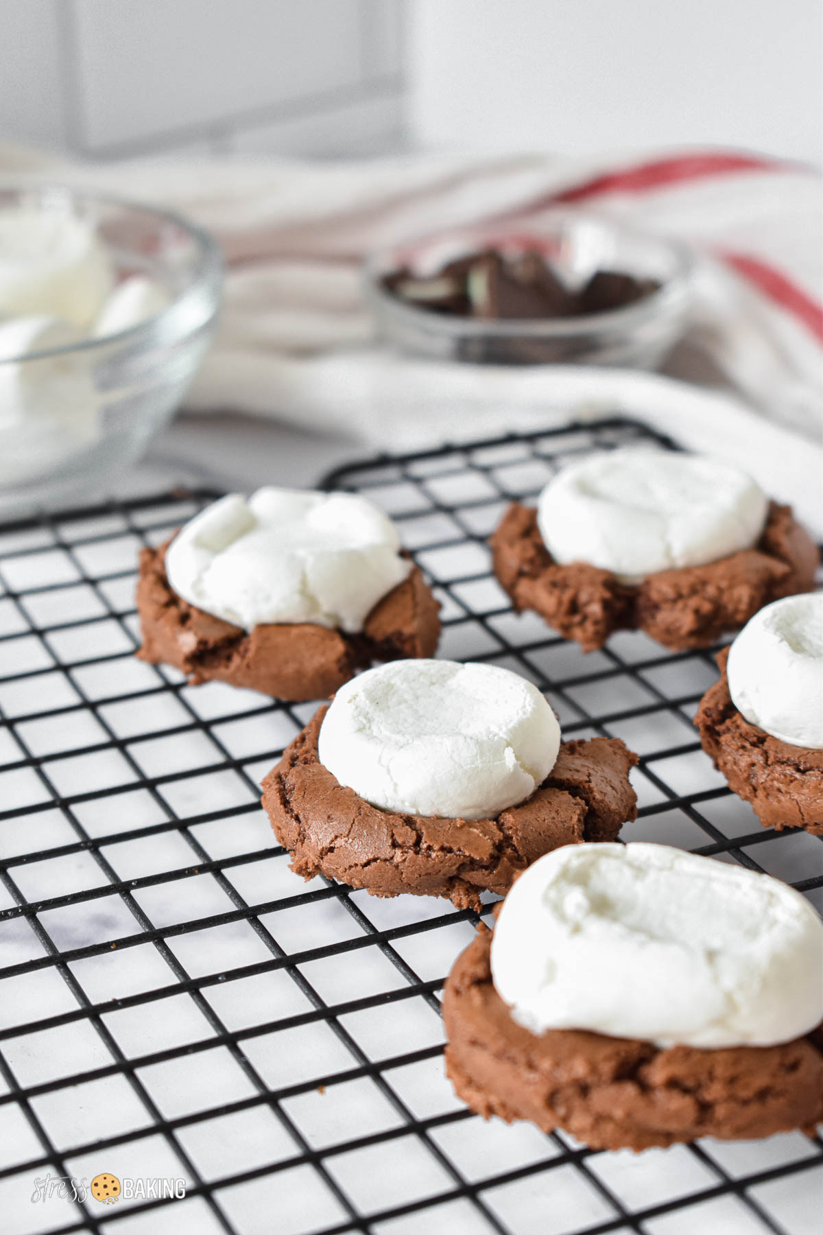 Crackly chocolate cookies topped with marshmallows on a black wire cooling rack