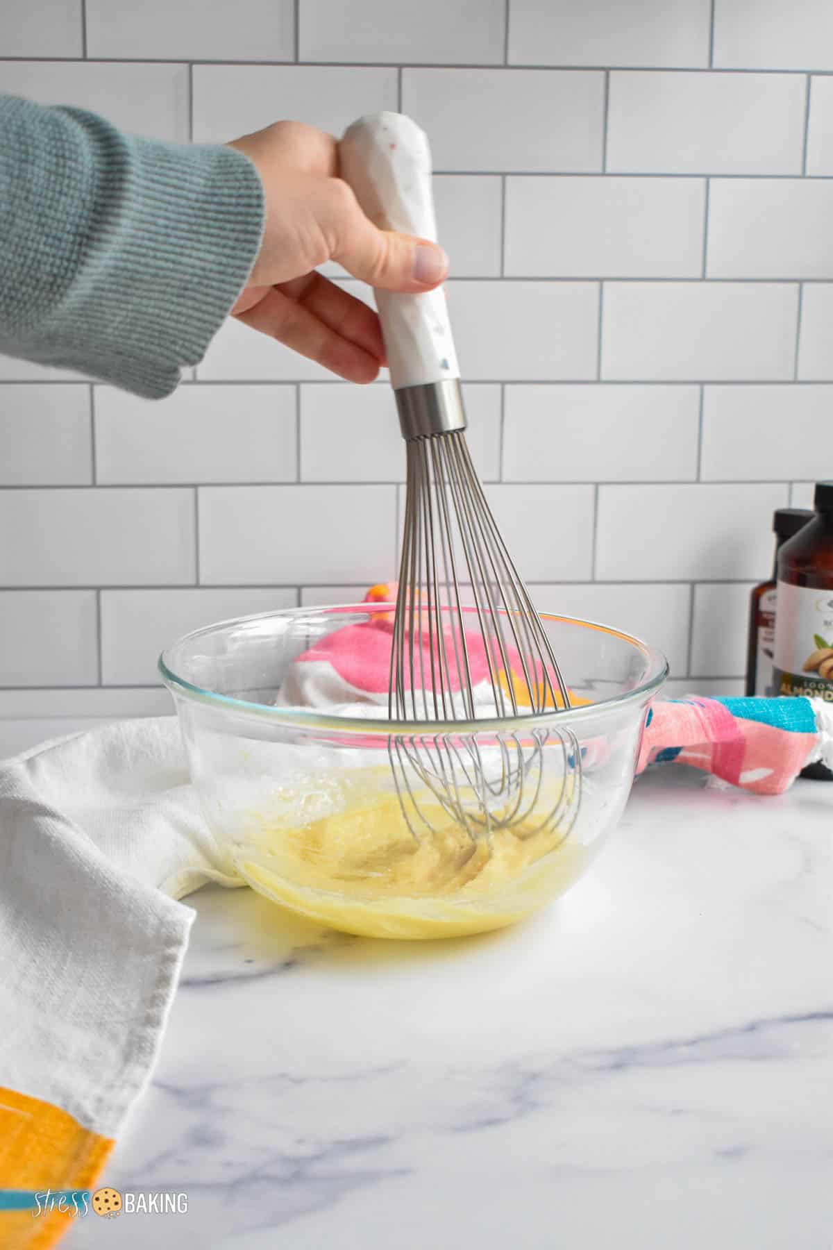 Whisking a yellow batter in a glass mixing bowl