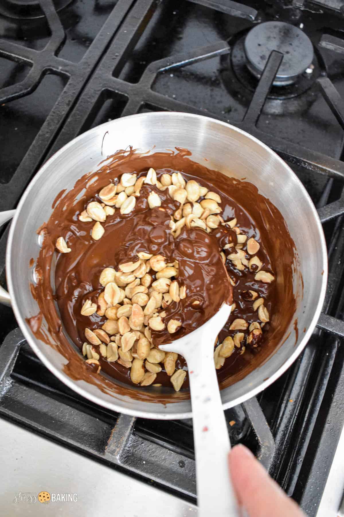 Peanuts being stirred into melted chocolate in a saucepan