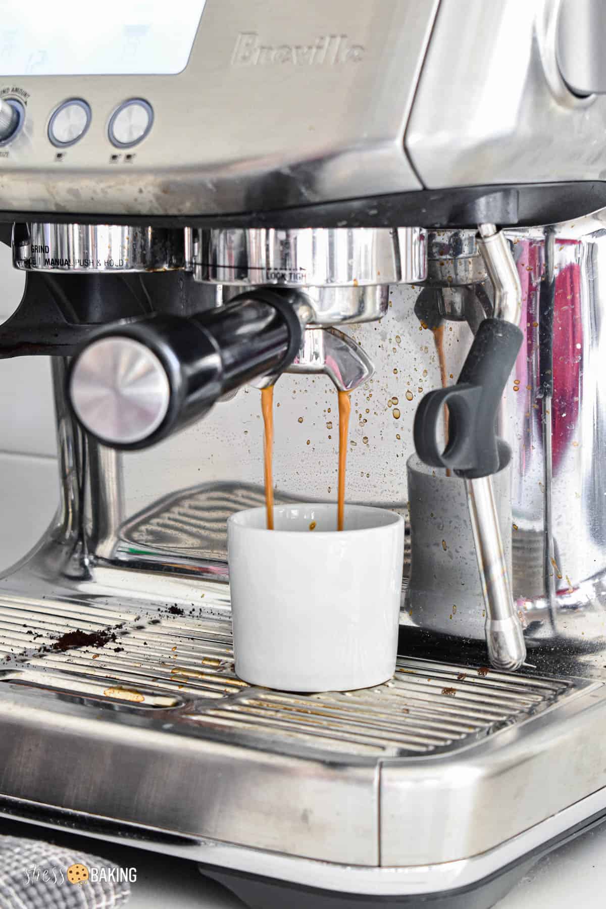 Espresso being brewed from a Breville into a white demitasse cup