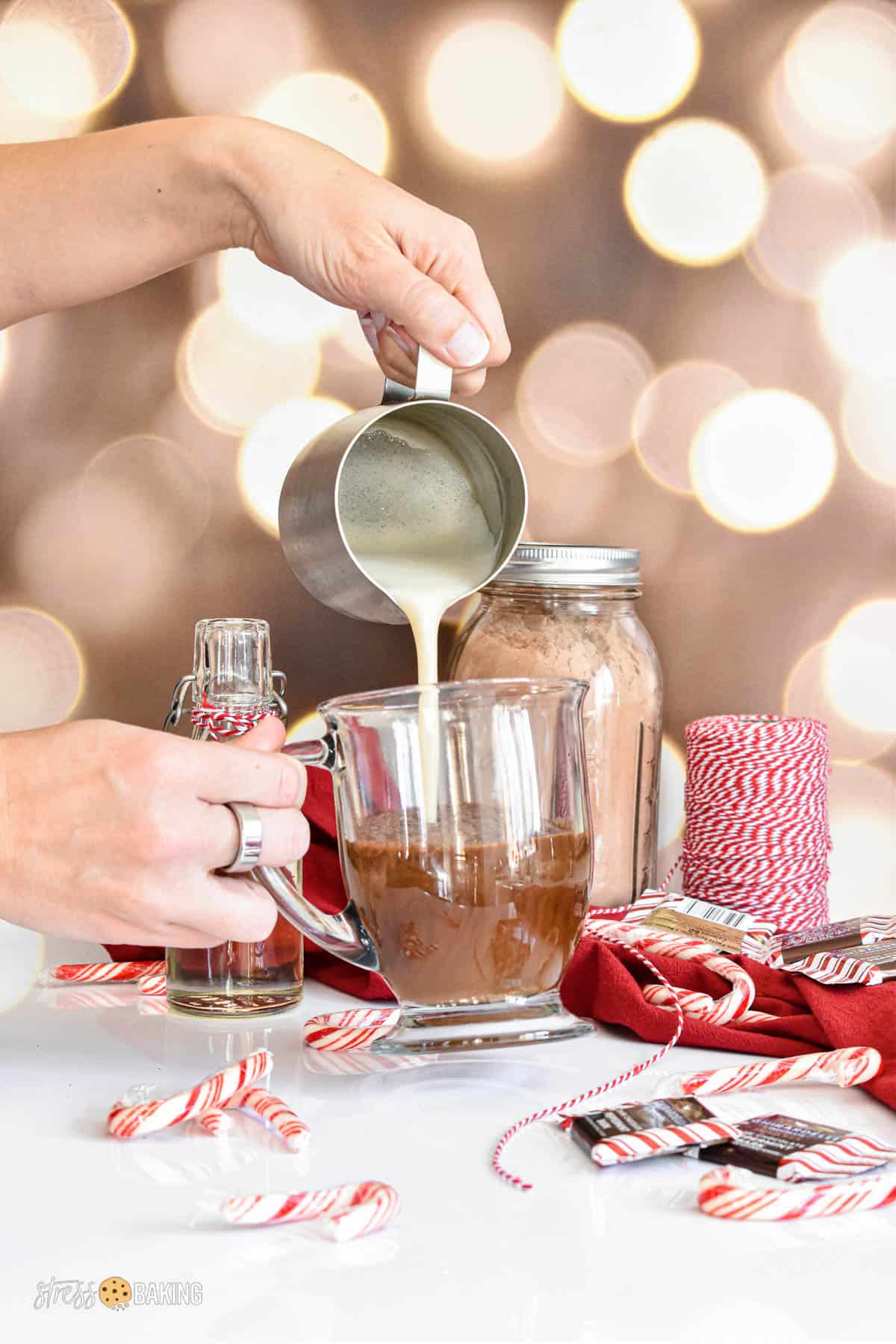 Steamed milk being poured into a clear mug of peppermint mocha