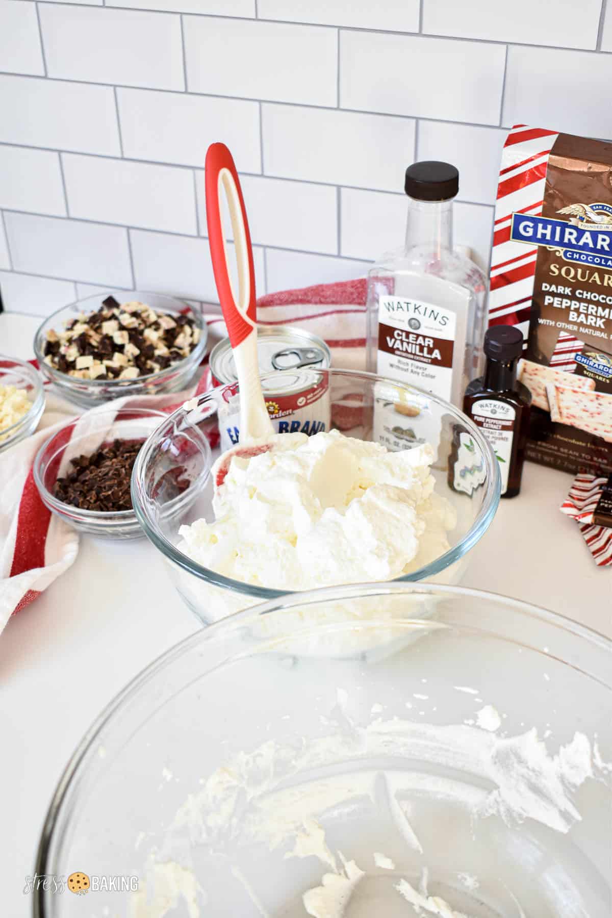 A bowl of homemade whipped cream next to ingredients for peppermint bark ice cream