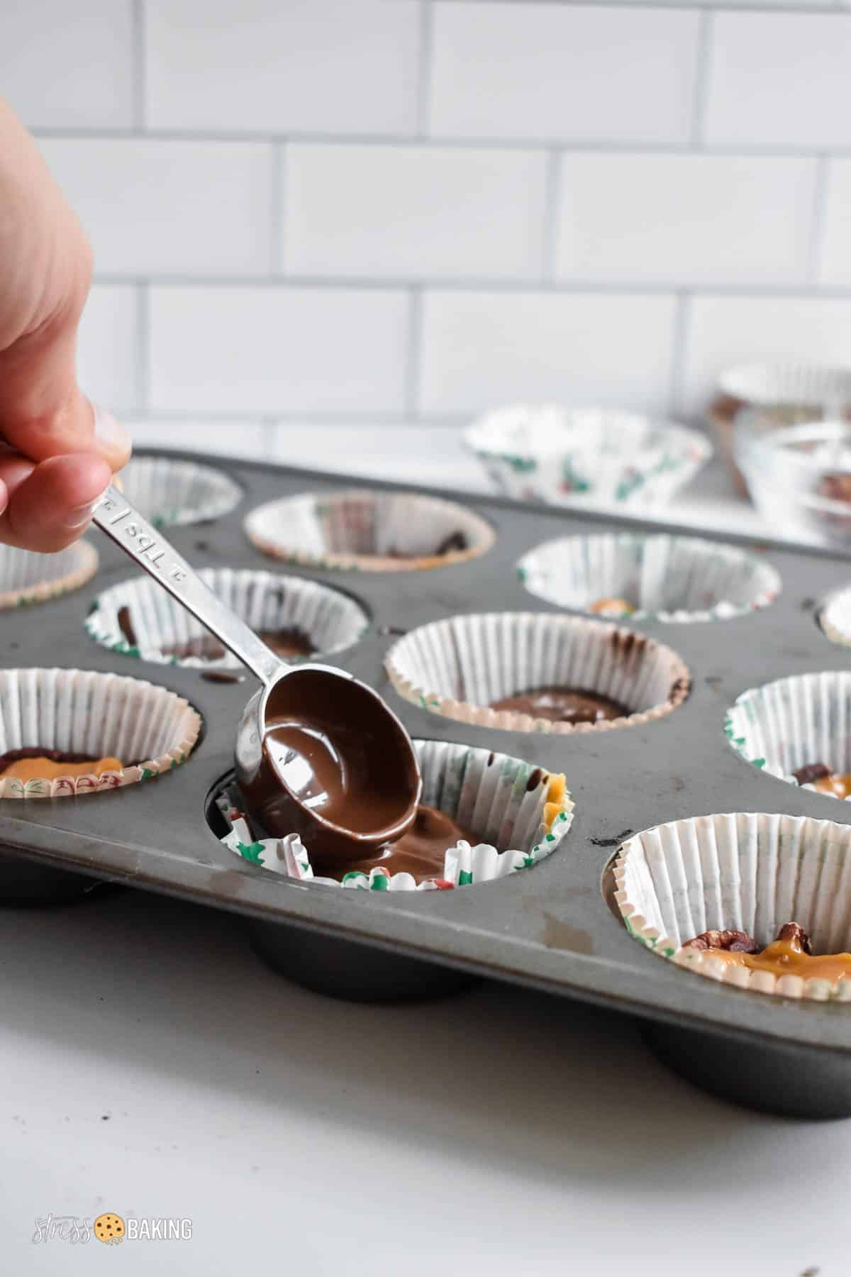 Melted chocolate being smoothed out in a muffin tin