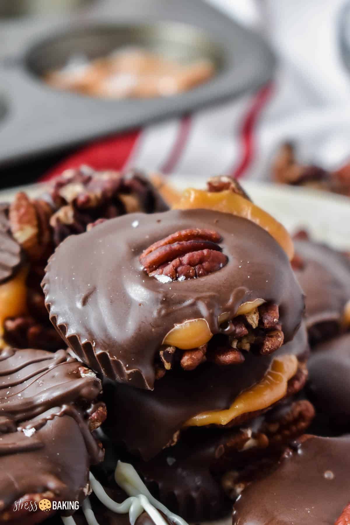 Stack of homemade turtle candy topped with chocolate and pecans