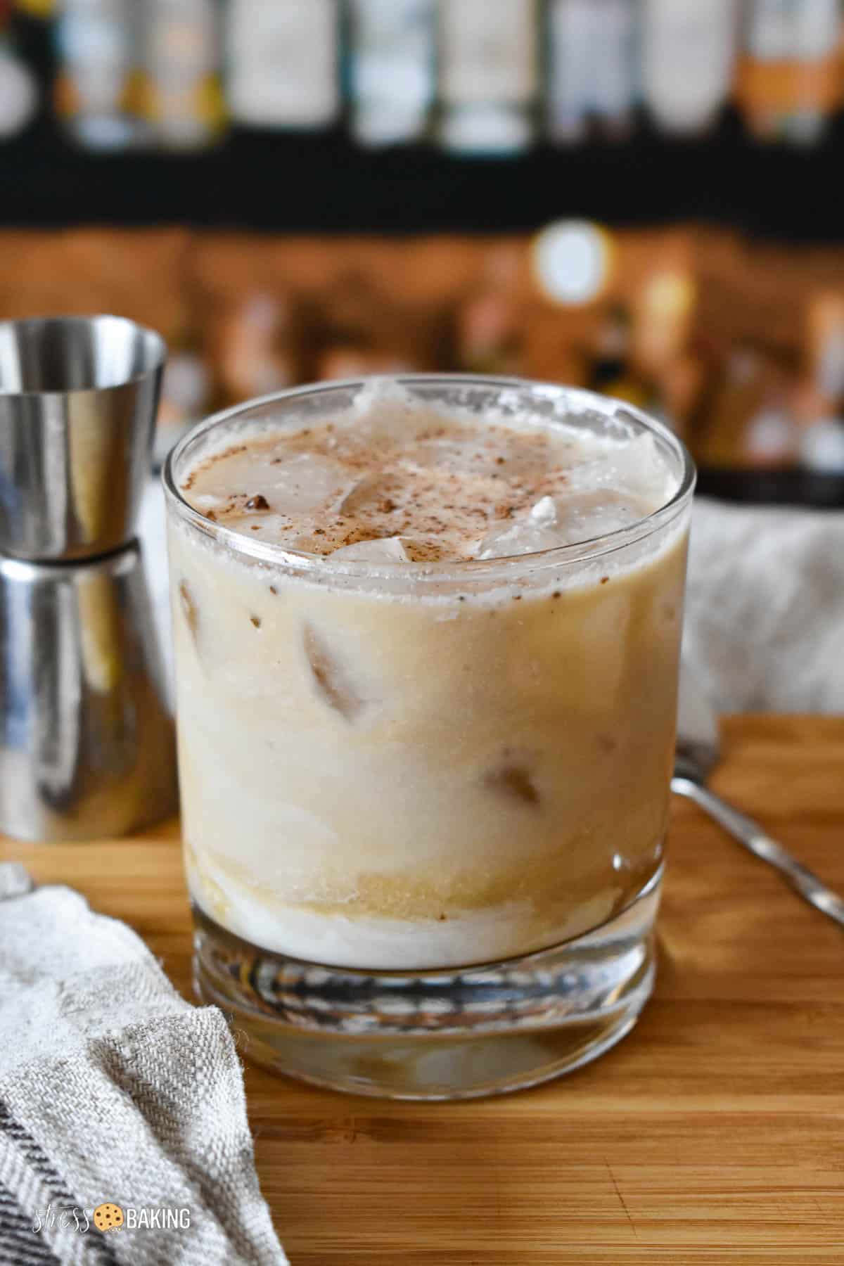 White Russian cocktail in a clear old fashioned rocks glass on a wood cutting board