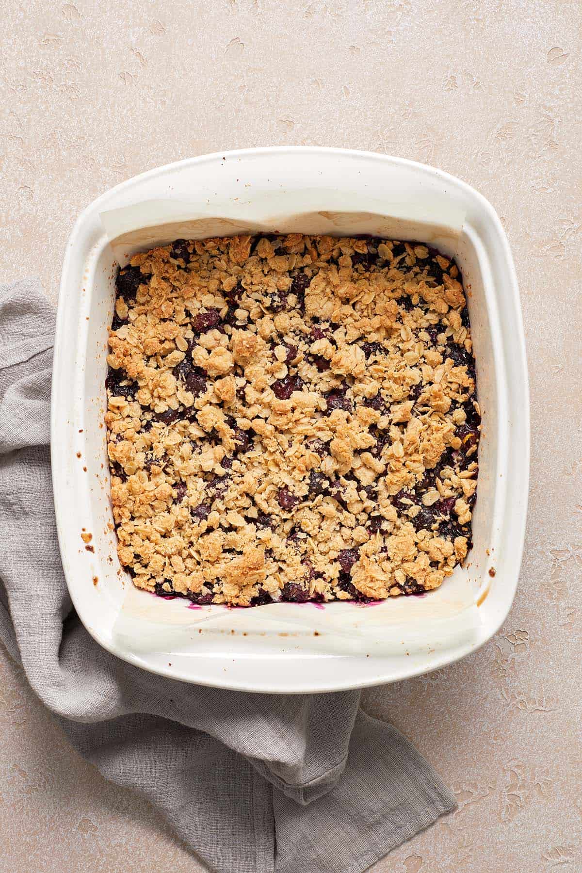 Square white baking dish filled with golden blueberry oatmeal mixture that was freshly baked