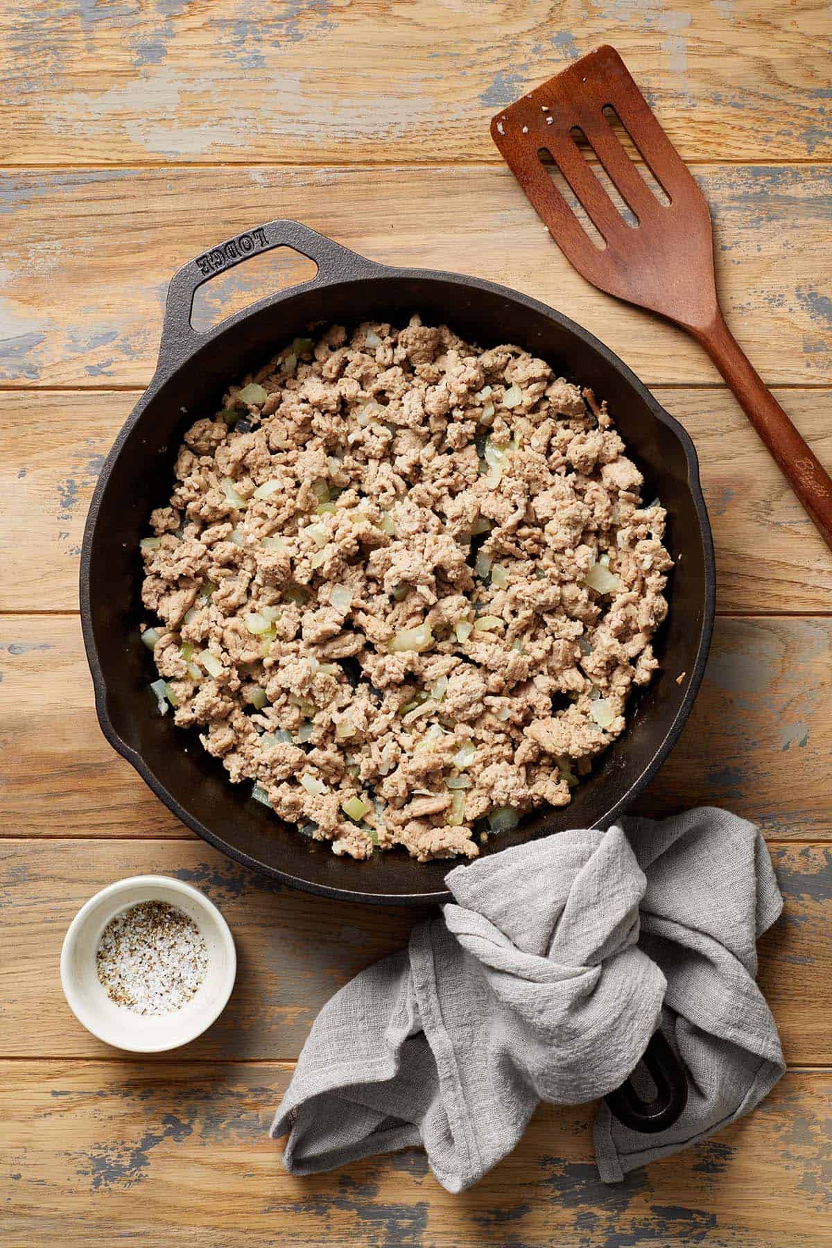 Ground turkey in a skillet on a wooden surface