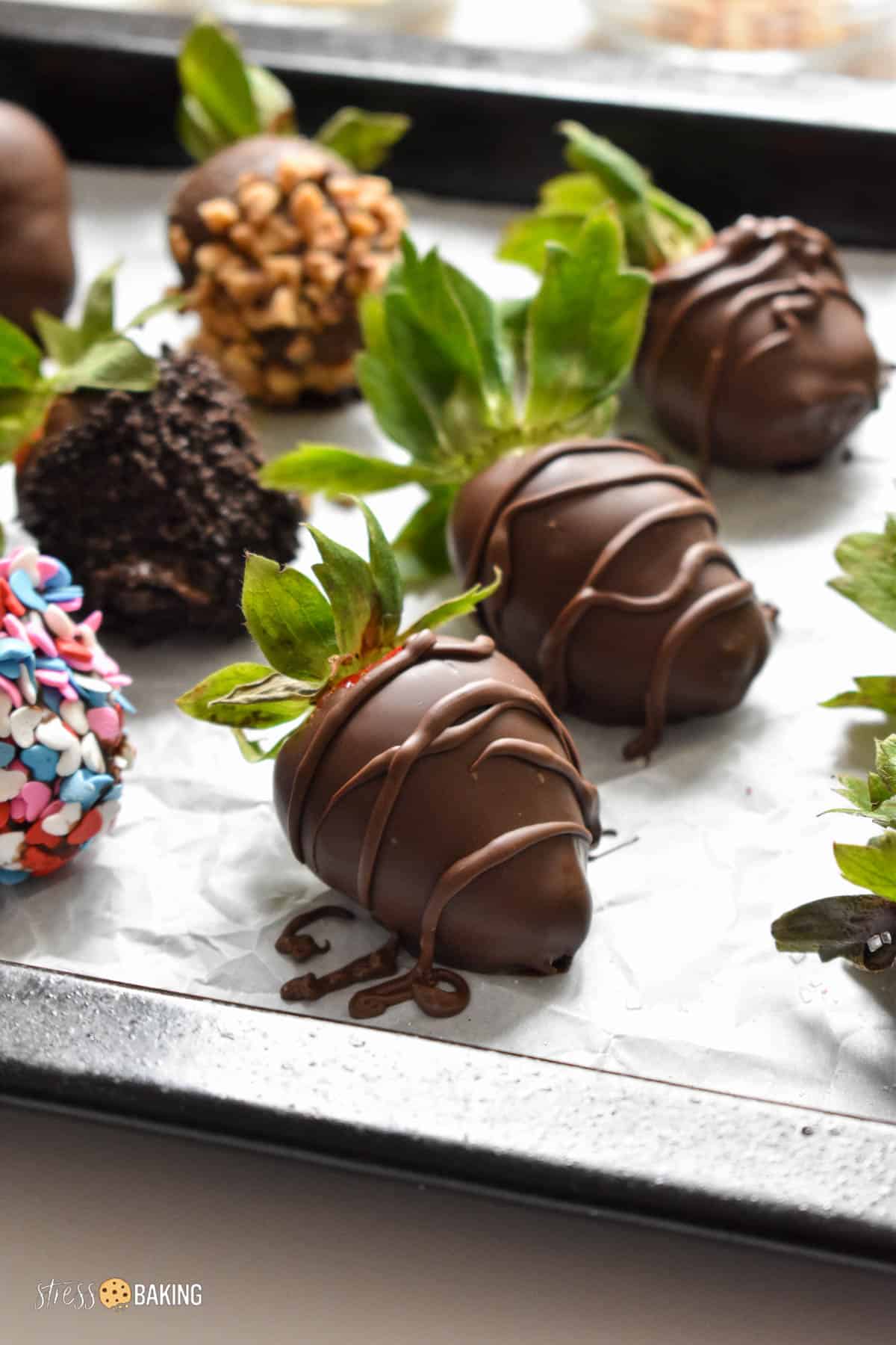 Decorated chocolate covered strawberries setting on parchment paper