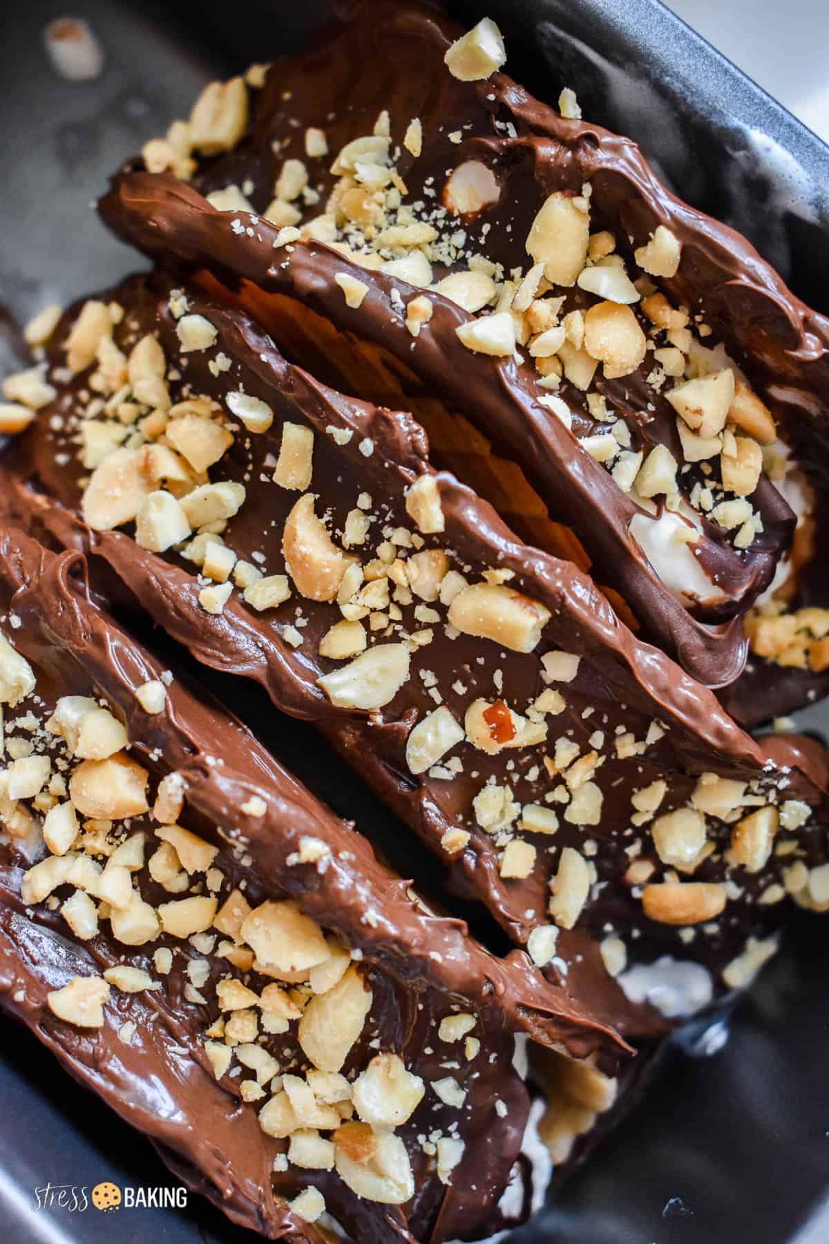 Homemade choco tacos side by side in a loaf pan topped with chocolate and chopped peanuts
