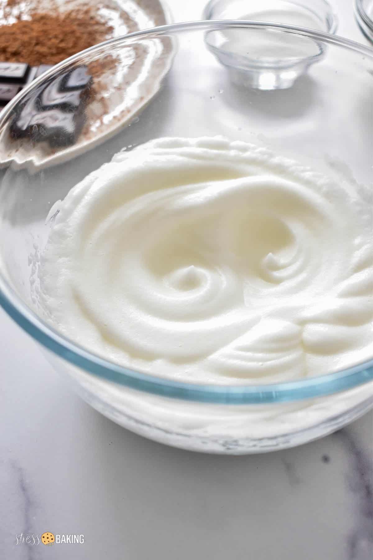Whipped egg whites in a clear mixing bowl