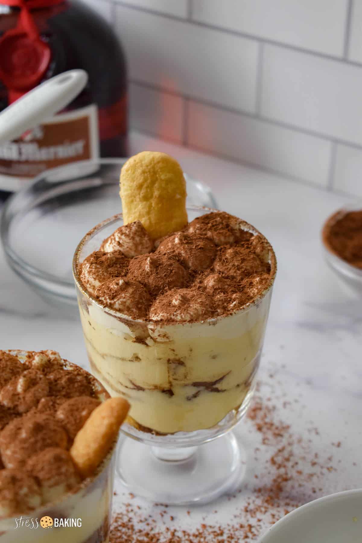 Tiramisu in a trifle dish topped with a dusting of cocoa powder