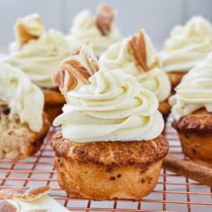 Cinnamon roll cupcake piled high with swirls of cream cheese frosting