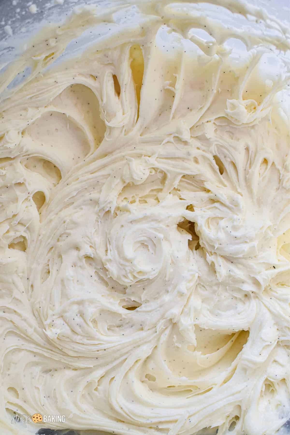 Speckled cream cheese frosting in a clear mixing bowl