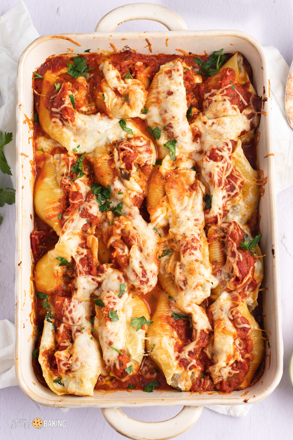 A baking dish of golden cheesy stuffed shells topped with parsley