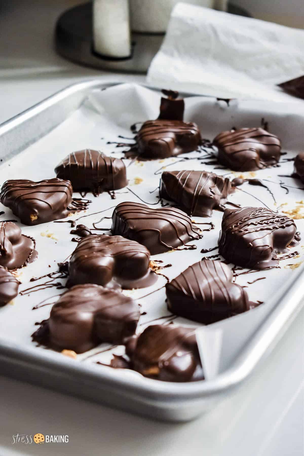 Chocolate dipped hearts drizzled with chocolate on parchment paper