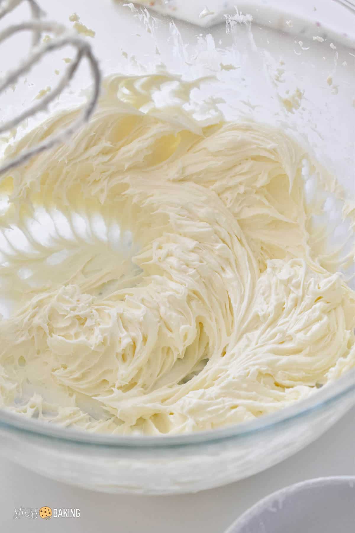 Whipped cream cheese frosting in a clear mixing bowl