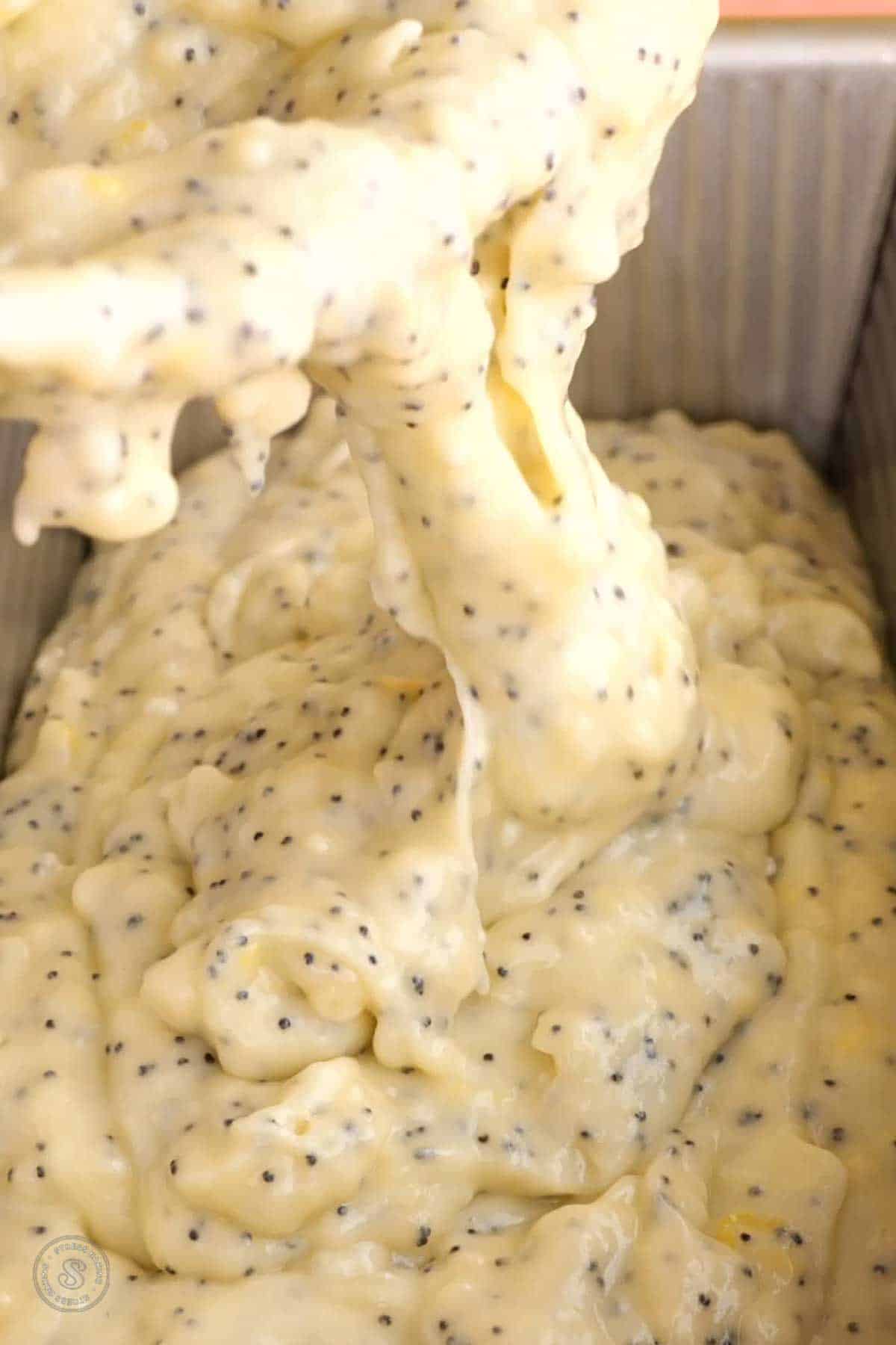 Lemon poppy seed batter being poured into a loaf pan