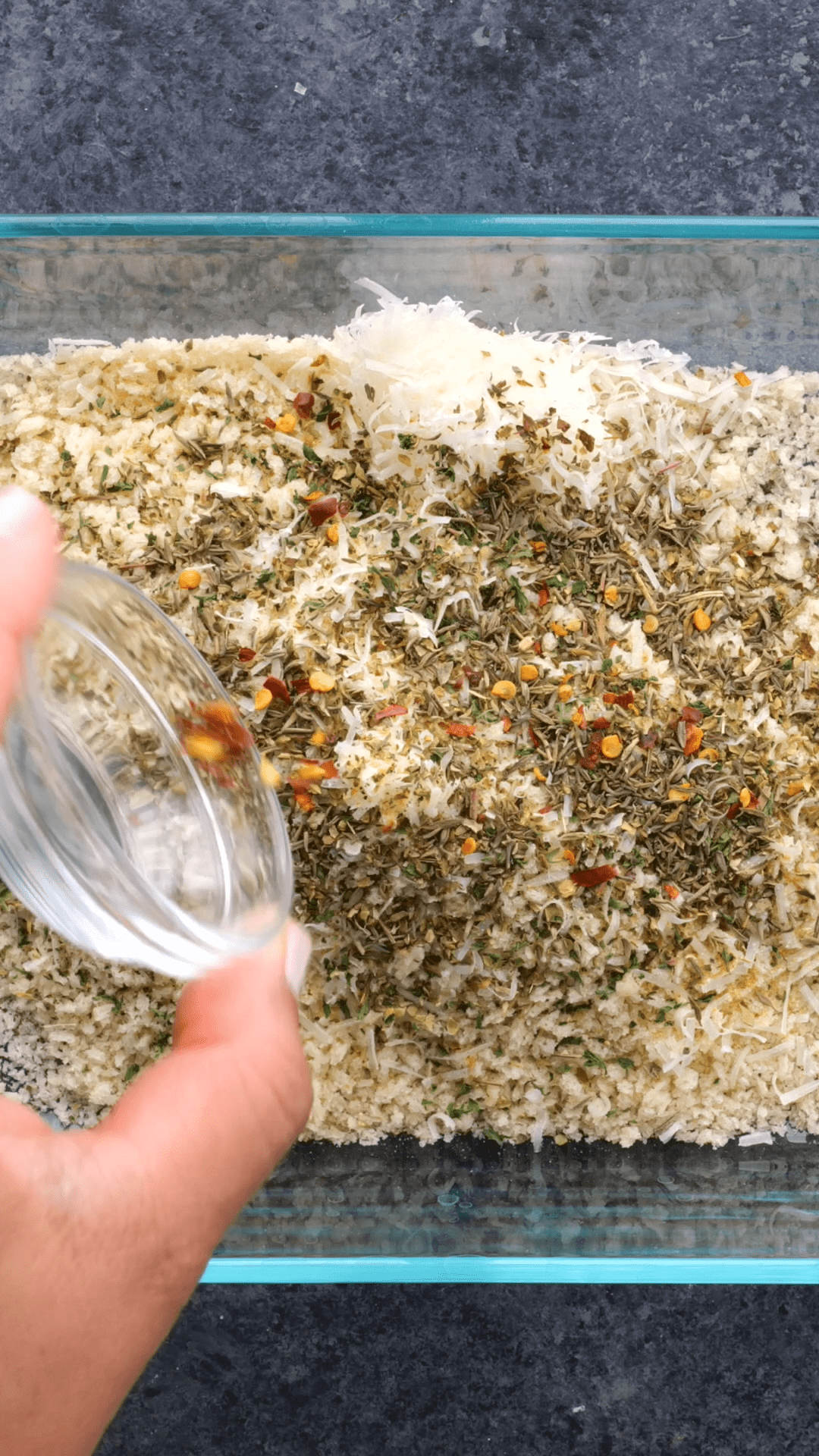 Mixing together a breadcrumb mixture in a clear dish