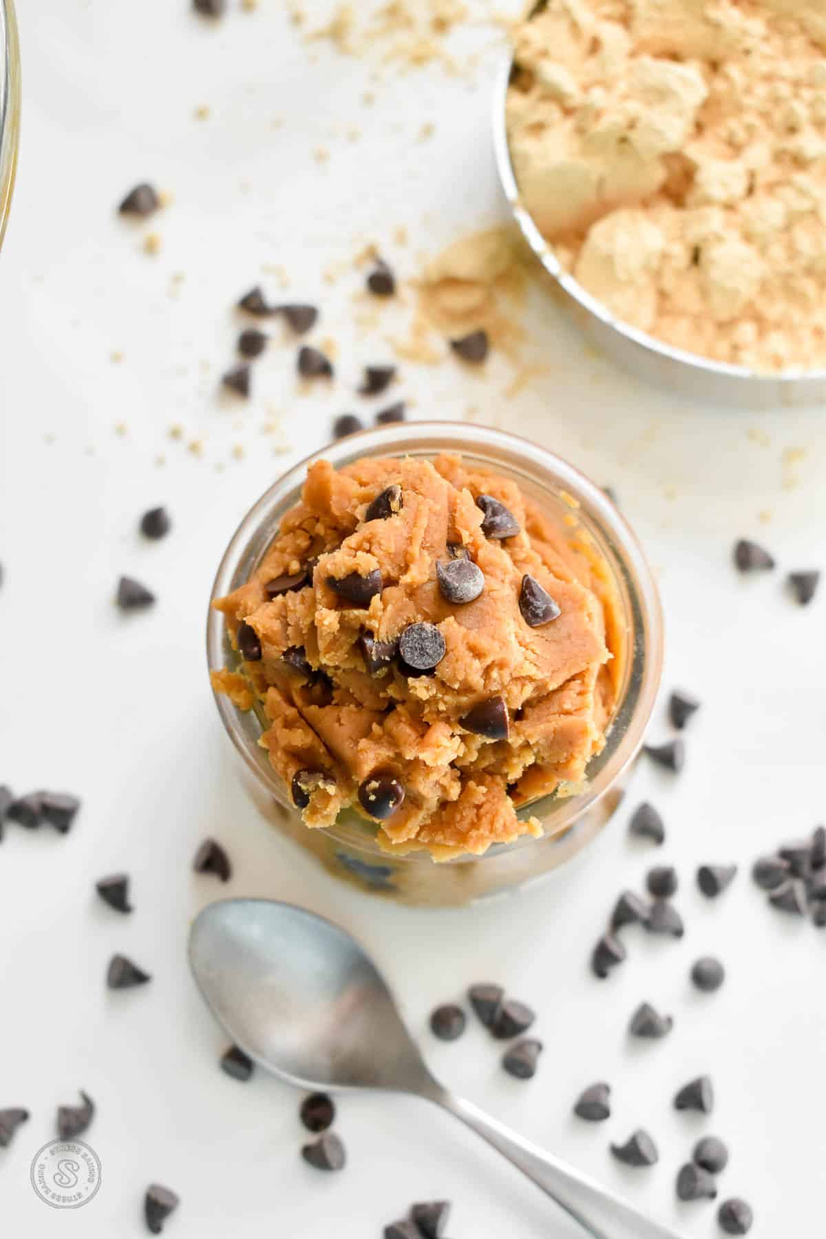 A small clear jar stuffed with peanut butter cookie dough dotted with mini chocolate chips