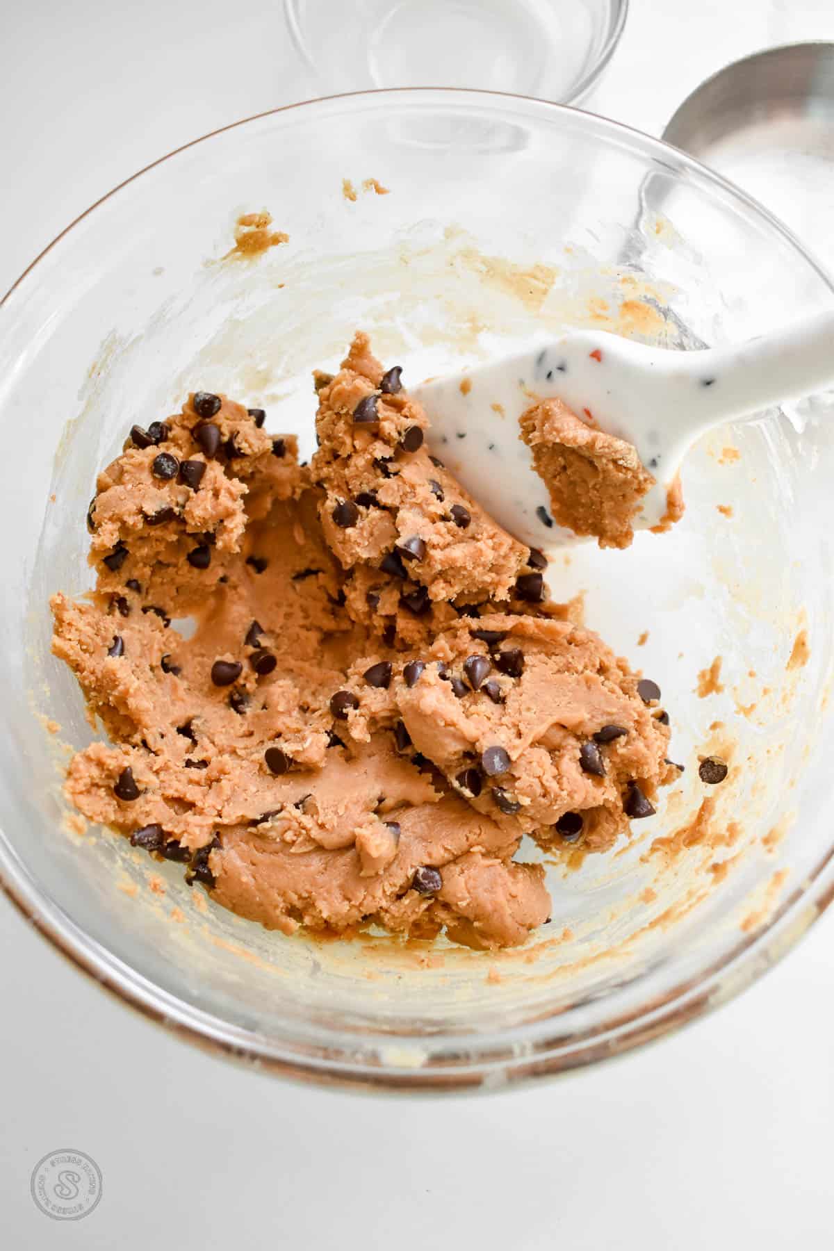 Peanut butter cookie dough dotted with mini chocolate chips in a small mixing bowl