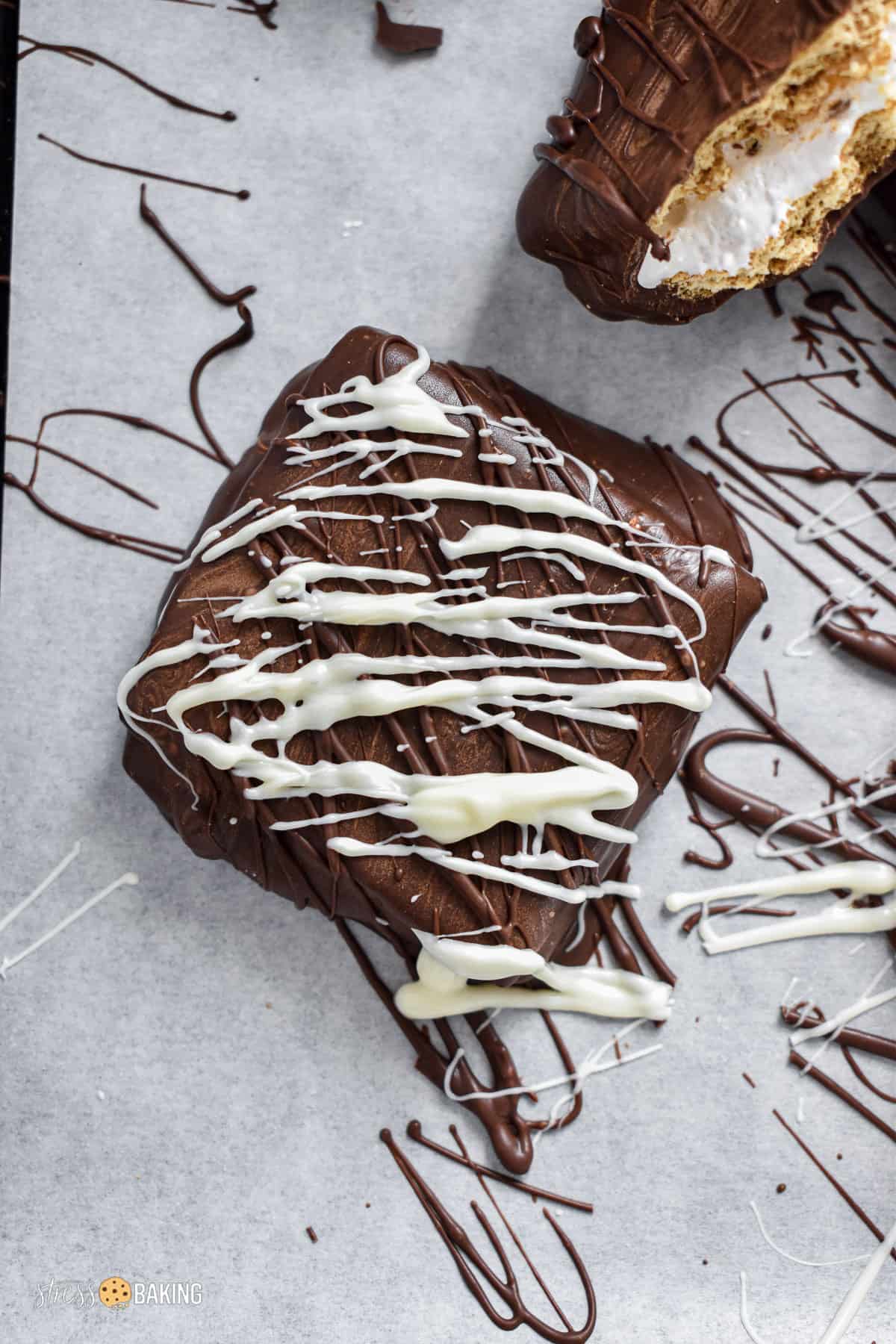 Square chocolate cookie drizzled with chocolate and white chocolate sitting on parchment paper