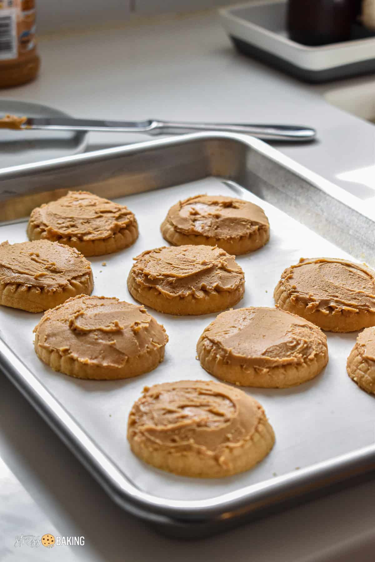 Shortbread cookies topped with peanut butter on a baking sheet