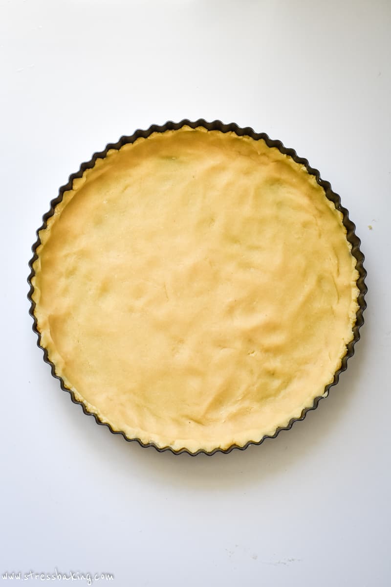 Golden colored crust pressed into a large round tart pan