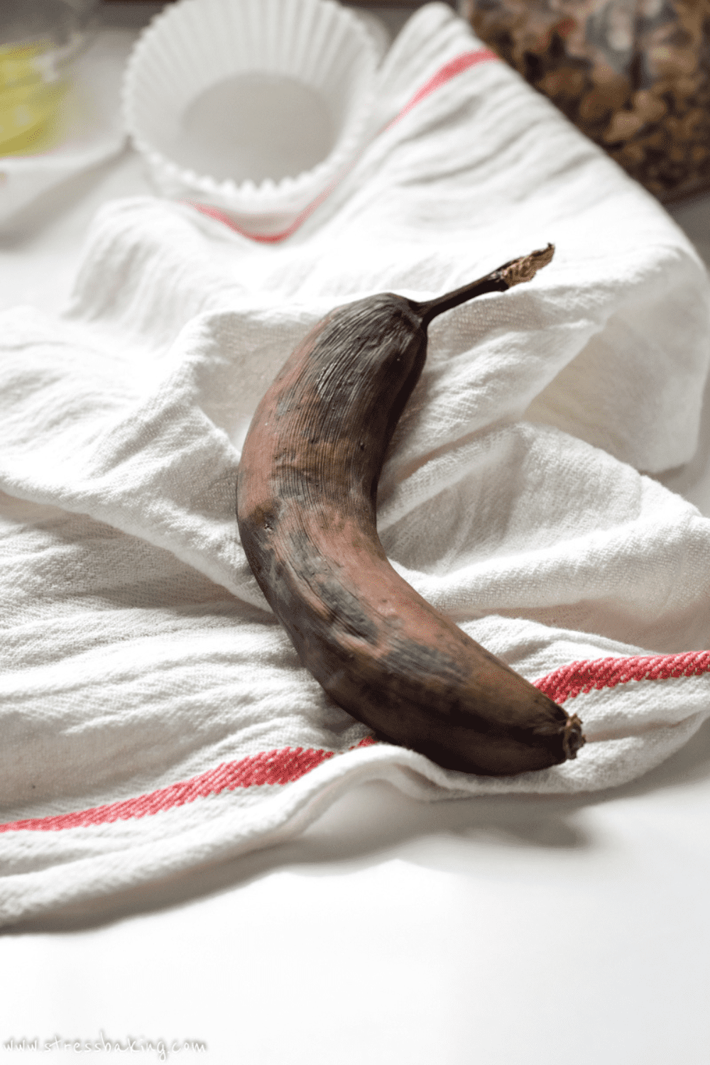 Brown and black overripe banana on a white and red dishtowel