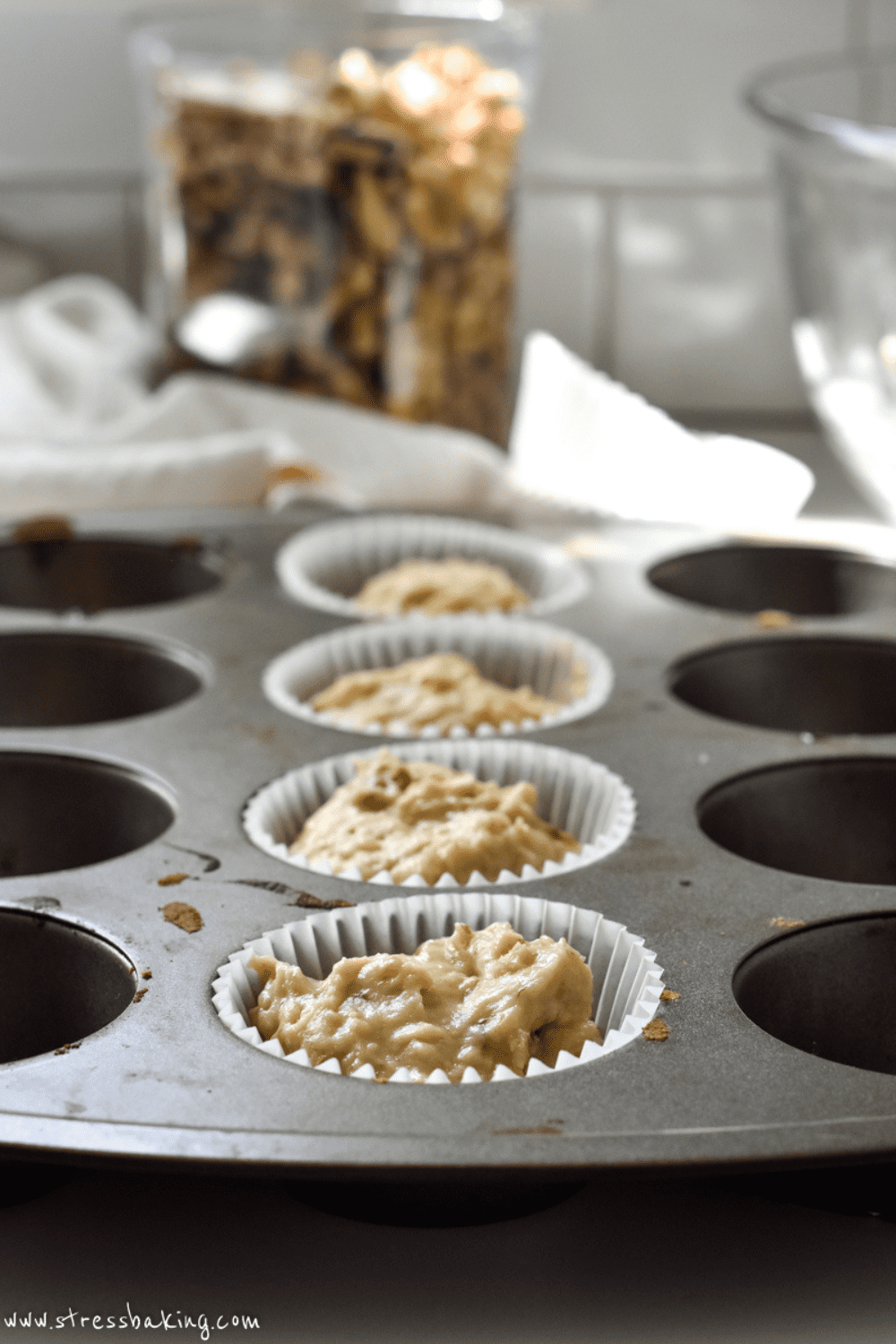 Muffin batter in white liners inside a muffin pan