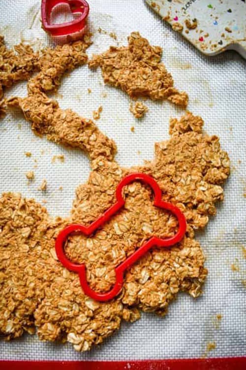 Dog treat dough being cut out with bright red cookie cutters