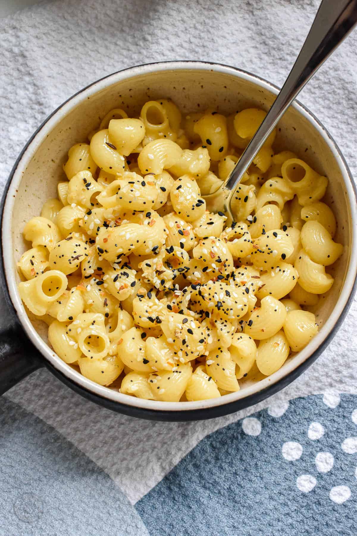 Short pasta noodles coated in thin sauce and topped with everything bagel seasoning