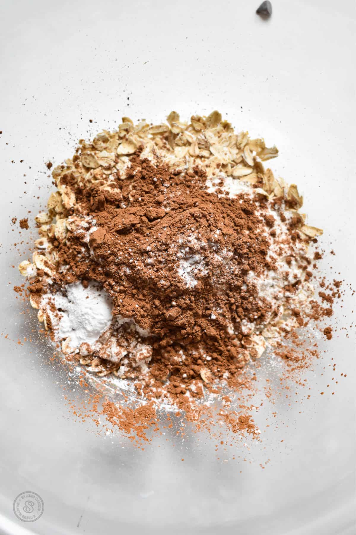 Dry ingredients topped with cocoa powder in a clear mixing bowl