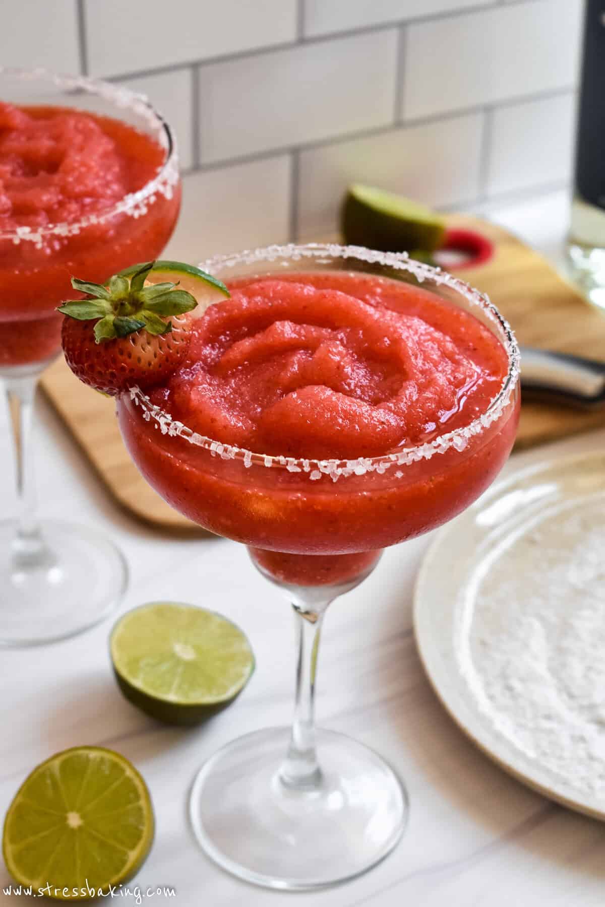 Bright red blended frozen strawberry margarita with strawberry and lime garnish