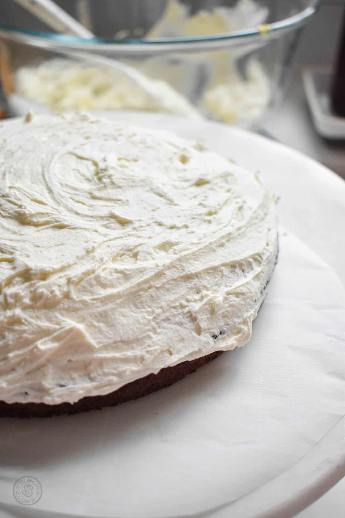 Whipped cream frosting spread across a round cake layer