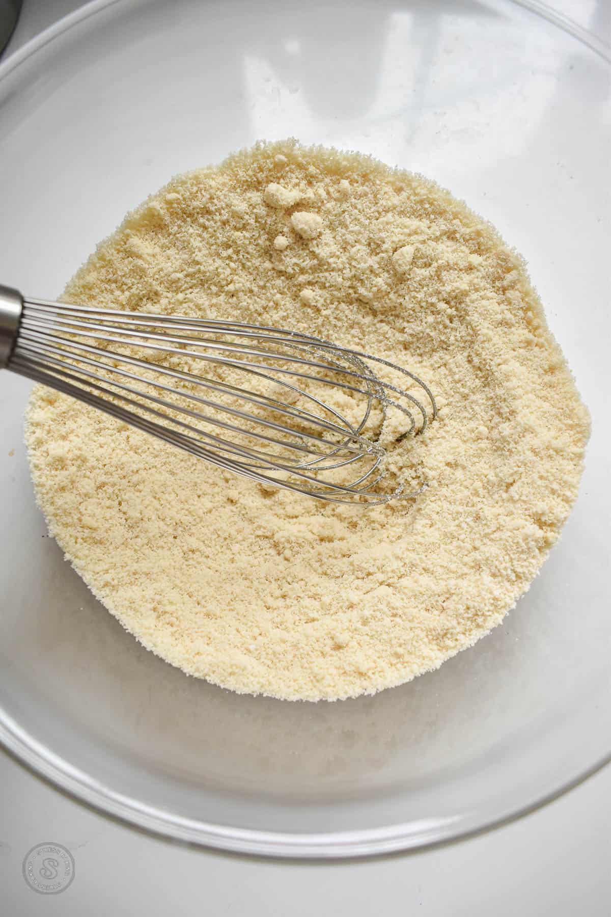 Almond flour mixture with a whisk in a clear mixing bowl