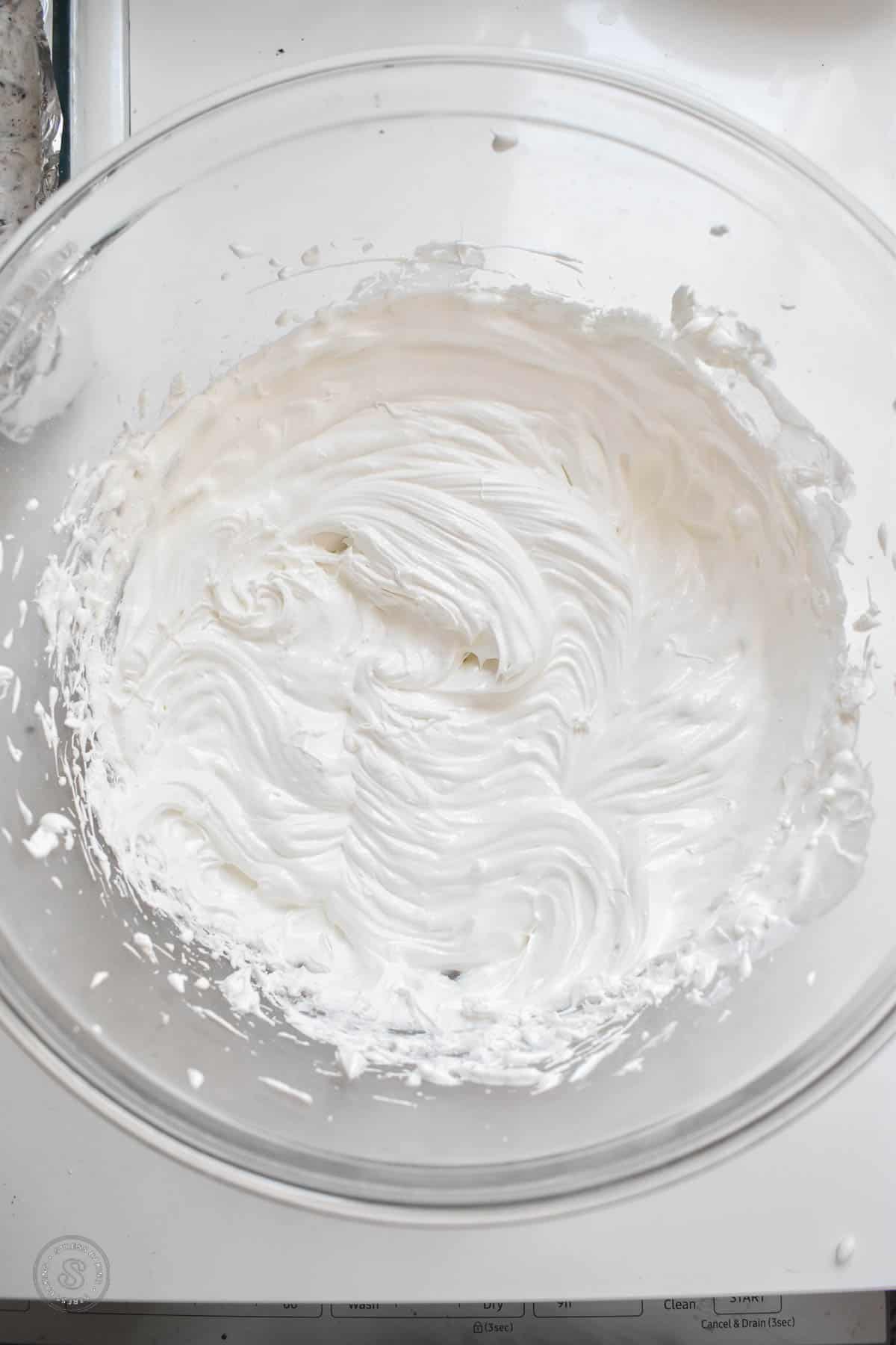 Whipped Cool Whip frosting in a clear mixing bowl