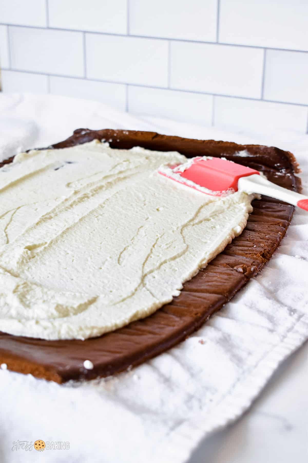 Spreading whipped cream on a thin layer of chocolate cake