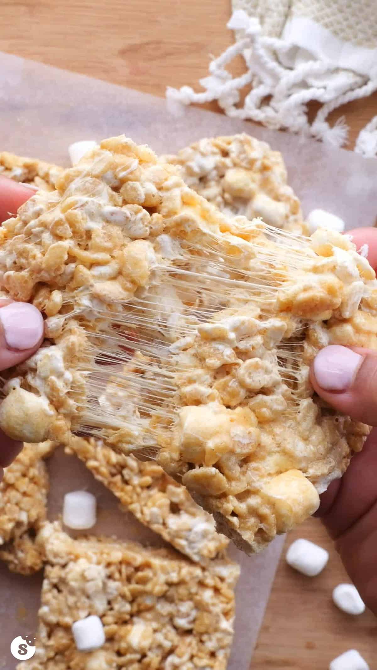A big bar of fluffernutter rice krispie treats being pulled apart to show the gooey marshmallows