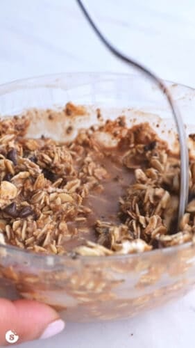 Peanut butter chocolate chip oats being stirred in a bowl with a fork