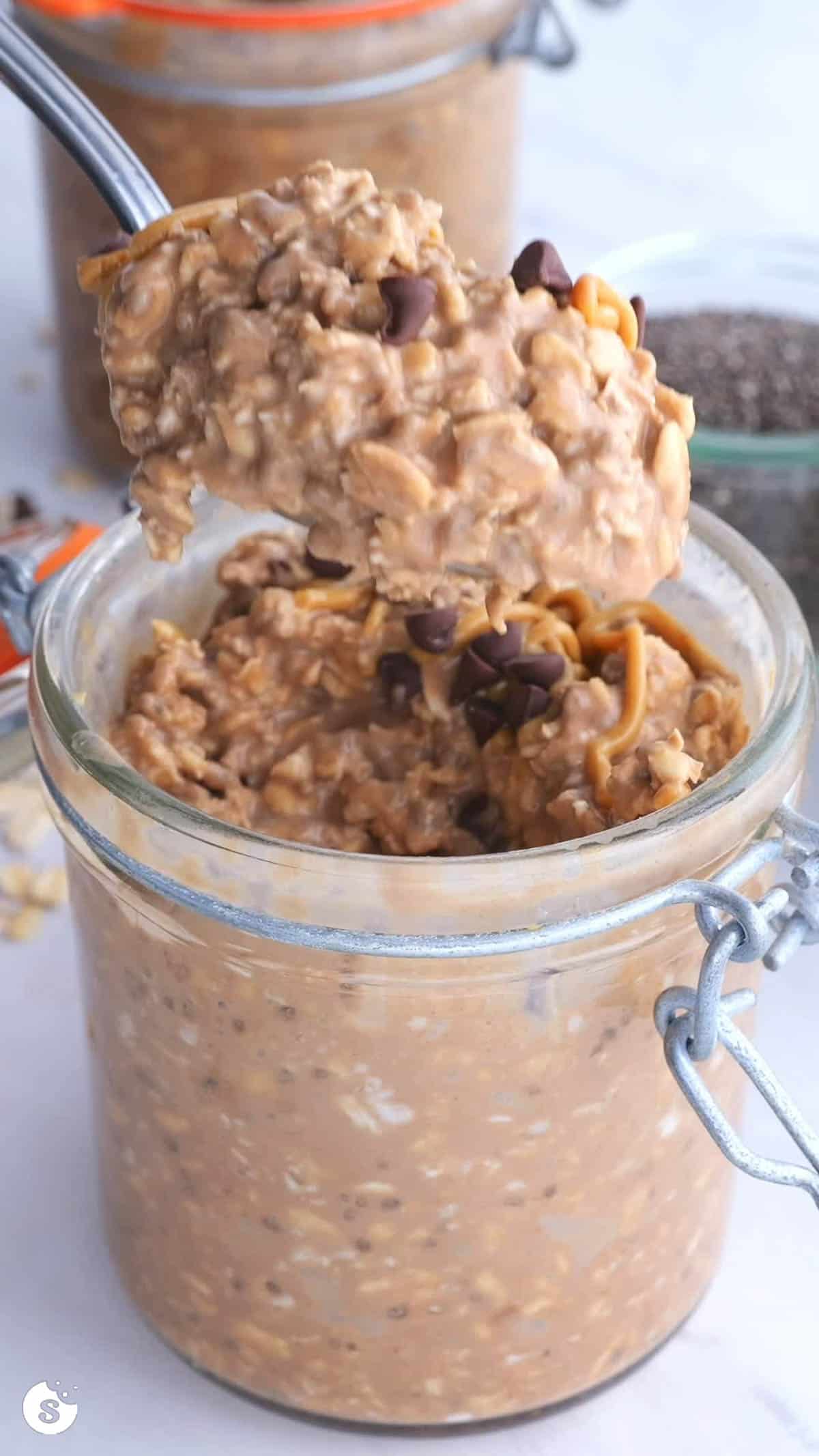 A big spoonful of no bake cookie overnight oats being scooped out of a jar